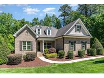 Beautiful brick home featuring dormer windows and mature landscaping, set against a backdrop of lush trees at 7108 Carries Reach Way Way, Raleigh, NC 27614