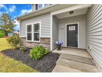 Inviting front entrance with a stylish black door, flower pot, and well-maintained landscaping at 1013 Fieldmere Pl, Wendell, NC 27591