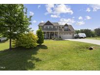 Charming two-story home with a well-manicured lawn, two-car garage, and inviting front porch at 123 Hawick Ct, Zebulon, NC 27597
