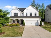 Beautiful two-story home featuring a two-car garage and a welcoming front porch with rocking chairs at 128 Highland Grove Way, Fuquay Varina, NC 27526