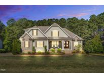 Charming two-story home featuring stone accents, a covered front porch and mature trees at 128 Paraggi Ct, Clayton, NC 27527