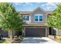 Charming townhome featuring stone accents, a two-car garage, and a well-maintained front yard at 1314 Catch Fly Ln, Durham, NC 27713