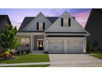 Charming home featuring a two-car garage, landscaped yard, and stylish black and white accents at 1513 Armscroft Lane, Apex, NC 27502