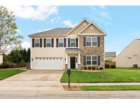 Two-story home boasts a two-car garage, manicured lawn, and stone and siding exterior accents at 203 Green Pasture Rd, Mebane, NC 27302