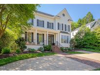 Stunning white brick two-story home with black shutters, a covered porch, and professional landscaping at 2306 Byrd St, Raleigh, NC 27608
