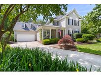 Charming two-story home featuring a well-manicured lawn, a driveway, and a covered porch adorned with American flags at 30150 Walser, Chapel Hill, NC 27517