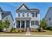 Charming two-story home featuring a welcoming porch with a blue front door and beautiful landscaping at 3224 Wishing Well Wynd, Apex, NC 27502