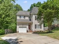 Charming two-story home with a well-manicured lawn, attached garage, and mature trees at 408 Blooming Meadows Rd, Holly Springs, NC 27540