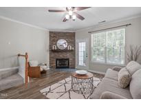 Cozy living room showcasing a stone fireplace, wood floors, and natural light from the large window at 4535 Sugarbend Way, Raleigh, NC 27606