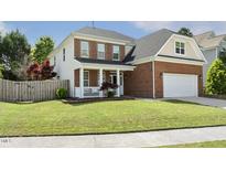 Charming two-story home with a partial brick facade, well-manicured lawn, and inviting front porch at 5213 Holly Ridge Farm Rd, Raleigh, NC 27616