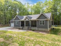 Charming exterior of a gray home featuring a covered porch, white trim, and a well-maintained front yard at 5402 Shealtiel Way, Rougemont, NC 27572