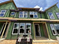 Modern townhome's exterior showcases large windows, green sheathing, and a brick pavers, offering a glimpse of contemporary living at 805 Fireship Rd, Fuquay Varina, NC 27526