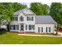 Charming two-story home with manicured lawn and mature trees, showcasing classic architectural details at 8600 Clivedon Dr, Raleigh, NC 27615