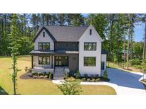 Stunning two-story home featuring a modern design, landscaped yard, and elegant entryway with stone and white plank siding at 904 Harrison Ridge Rd, Wake Forest, NC 27587