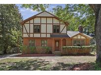 Charming Tudor-style home with brick facade, trimmed hedges, and beautiful landscaping at 101 Atchison St, Garner, NC 27529