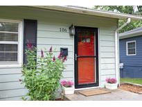 Charming home featuring a vibrant red front door, black shutters, and beautiful landscaping at 106 Eugene St, Carrboro, NC 27510