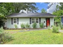 Charming home featuring light green siding, black shutters, a red front door, and lush landscaping at 106 Eugene St, Carrboro, NC 27510