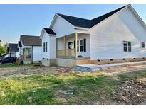 Charming home featuring white siding, a covered porch, and a well-maintained lawn at 1303 Whitsett St, Burlington, NC 27217