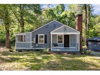 Charming home features a brick chimney and a welcoming front porch swing, perfect for enjoying peaceful afternoons at 1613 Kilmer Ter, Durham, NC 27703