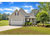 Charming single-Gathering home featuring a manicured lawn, two-car garage, and inviting front porch at 202 Reeder Branch Dr, Clayton, NC 27520