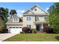 Inviting two-story home with a manicured lawn, attached garage, and charming front porch at 208 Willowbend Ln, Hillsborough, NC 27278