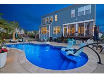 Backyard pool featuring sunbathing chairs and patio, set against a two-story home at 221 Obsidian Dr, Holly Springs, NC 27540