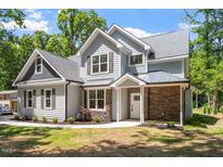 Charming two-story home featuring a stone accent wall and gray siding, complemented by well-manicured landscaping and a cozy entrance at 2405 Pearces Rd, Zebulon, NC 27597