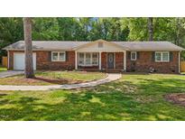 Charming brick home featuring a covered front porch with a swing and a well-manicured lawn at 2614 Cambridge Rd, Burlington, NC 27215