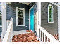 Inviting front door with brick steps, colorful mat and blue painted door at 404 Cary Pines Dr, Cary, NC 27513