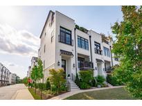 Stylish townhomes with white brick, black accents, manicured landscaping, and inviting front entrances at 411 Flat Rail Trl, Cary, NC 27511