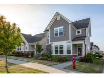Charming two-story home boasts stone accents, gray siding, a manicured lawn, and vibrant flowerbeds at 5200 Beckom St, Raleigh, NC 27616