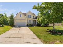 Charming yellow two-story home featuring a well-maintained lawn, two-car garage, and a welcoming front porch at 9701 Precious Stone Dr, Wake Forest, NC 27587