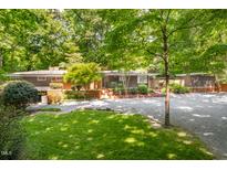 Beautiful single-story home with a well-manicured lawn and mature trees creating a private, park-like setting at 1111 Sourwood Cir, Chapel Hill, NC 27517