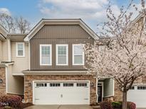 Charming townhome with stone accents, a two-car garage, and a beautiful blooming tree in the front yard at 149 Wards Ridge Dr, Cary, NC 27513