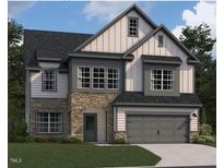Two-story home featuring stone accents, a gray two-car garage, and a dark gray roof at 1609 Malcus Ct # 67, Fuquay Varina, NC 27526