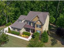 Two-story home featuring lush landscaping, green lawn, neutral colored exterior, and mature trees at 1820 Yates Wheel Way, Raleigh, NC 27606