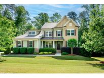 Charming two-story home featuring a well-manicured lawn and lush landscaping at 1820 Yates Wheel Way, Raleigh, NC 27606