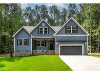 Charming home with blue siding, black shutters, a two car garage, and a well manicured green lawn at 249 Rawhide Dr, Louisburg, NC 27549