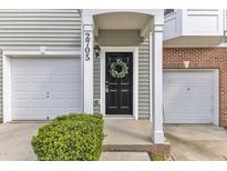 Charming townhome entrance with black door, garage and welcoming wreath at 2705 Wyntercrest Ln, Durham, NC 27713