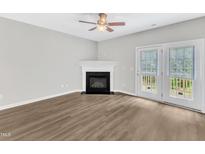 Bright living room features a cozy fireplace, ceiling fan, and access to the outdoors via french doors at 2705 Wyntercrest Ln, Durham, NC 27713