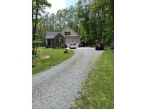 Charming home featuring a gravel driveway, brick accents, an attached garage, and a well-manicured lawn at 4072 Mackenzie Dr, Haw River, NC 27258