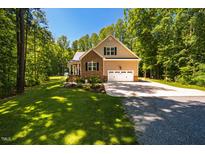Charming home featuring brick and tan siding, a two-car garage, and a well-manicured lawn at 4072 Mackenzie Dr, Haw River, NC 27258