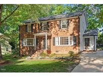 Charming two-story brick home with mature trees and professionally landscaped front yard at 7213 St Ledger Dr, Raleigh, NC 27613