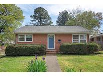 Charming brick home featuring a manicured lawn with lush shrubbery and a welcoming blue front door at 809 Leon St, Durham, NC 27704