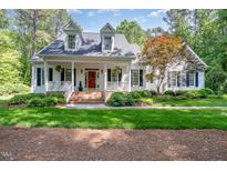 Charming home featuring a welcoming front porch, red door, and lush, manicured landscaping at 8304 Epping Forest Way, Wake Forest, NC 27587
