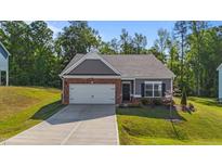 Charming single-story home featuring a brick and siding exterior, attached garage, and well-maintained landscaping at 94 Shooting Star Ln, Clayton, NC 27520