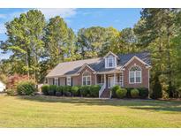 Charming home featuring a manicured lawn, brick accents, and a welcoming entrance at 100 Bradborne Cir, Clayton, NC 27520