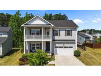Charming two-story home featuring a double-decker porch, neutral siding, and an attached two-car garage at 116 Chaseford Ct, Holly Springs, NC 27540