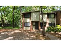 Charming two-story townhome with a brick facade and inviting front entrance nestled in a wooded setting at 1222 Teakwood Pl, Raleigh, NC 27606