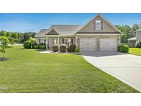 Charming home boasts a well-manicured lawn, an attached two car garage, and impeccable landscaping at 17 Kaki Ct, Selma, NC 27576